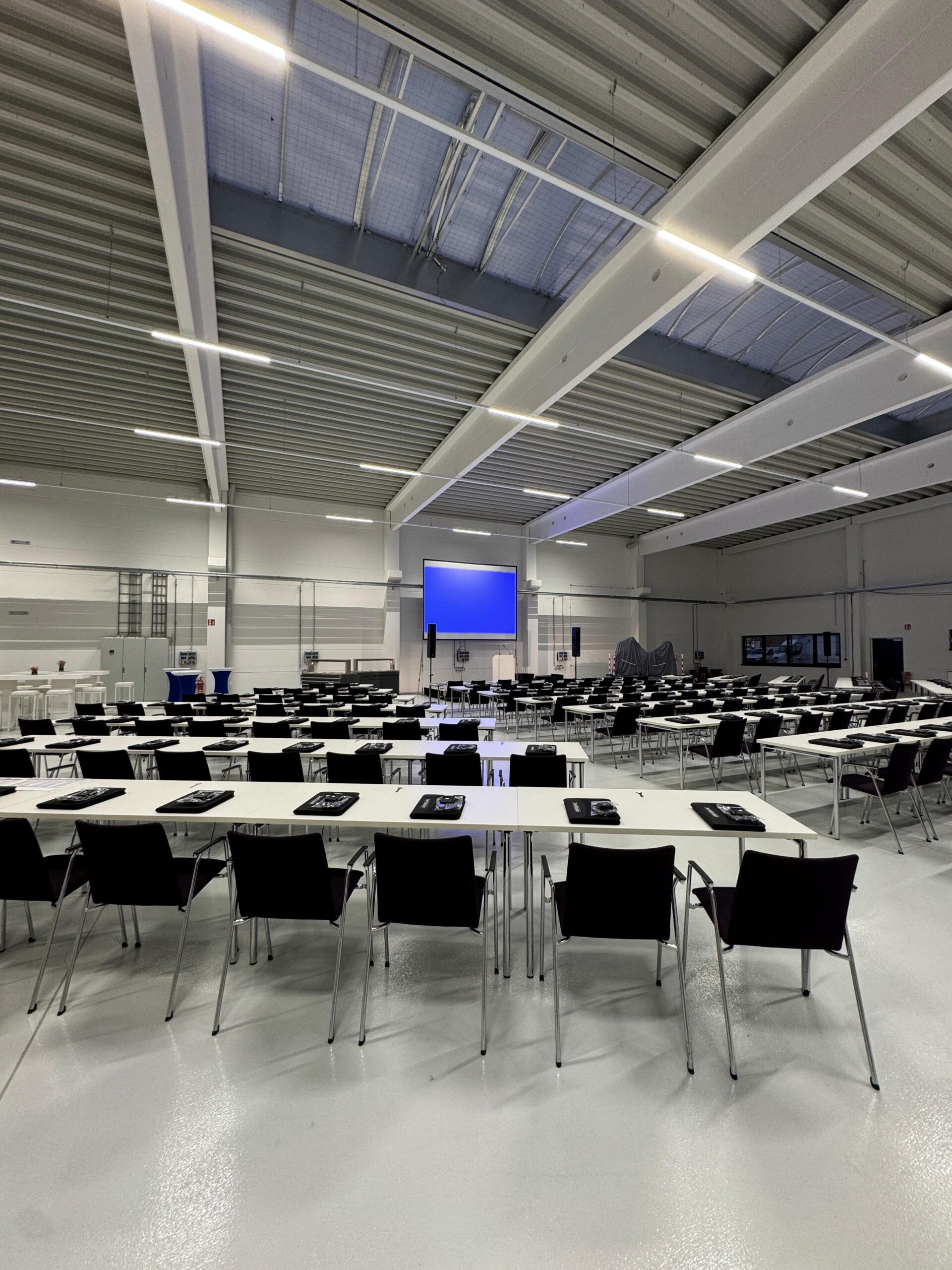 Bestuhlter Saal mit Bildschirm und Konferenztechnik bei einer Produktpräsentation